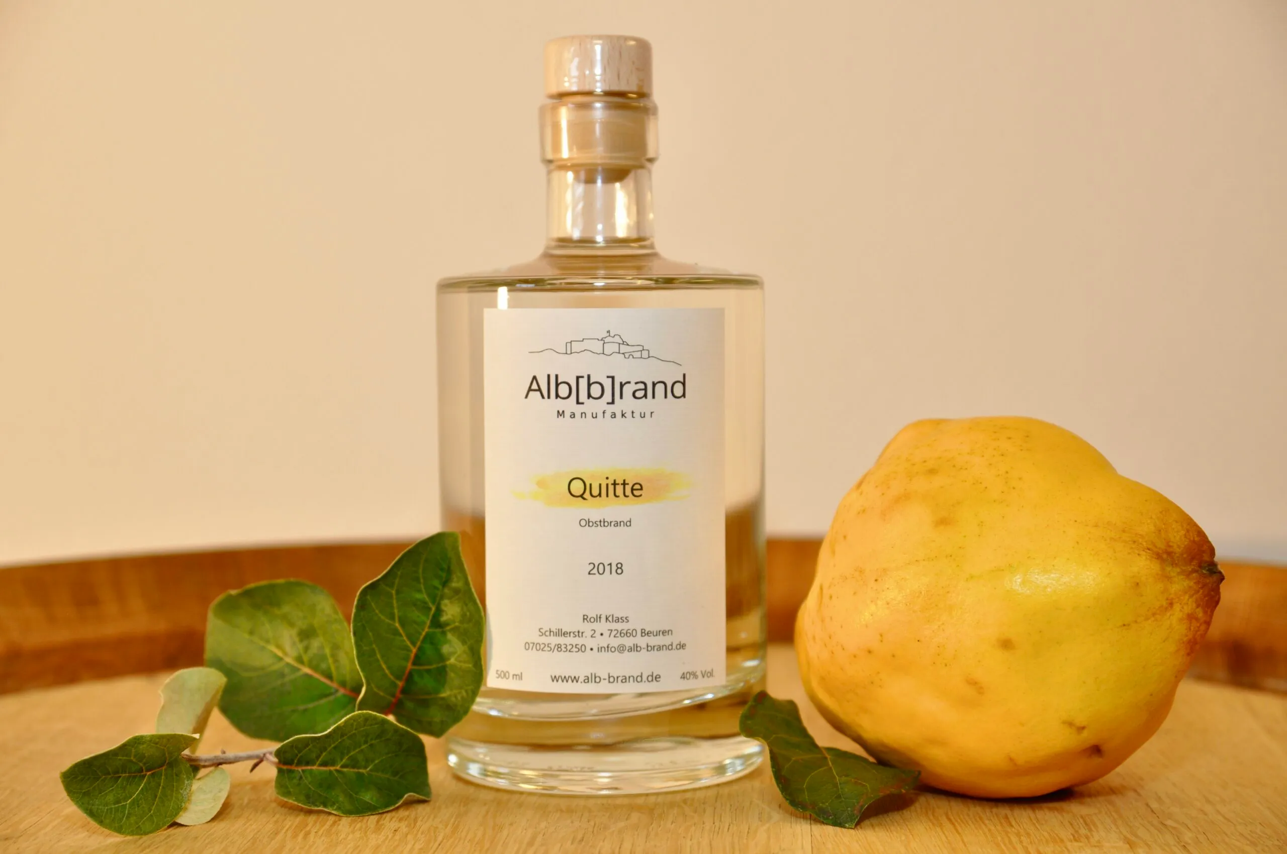 Flasche Quittenbrand mit frischer Quitte auf einem Holzfass