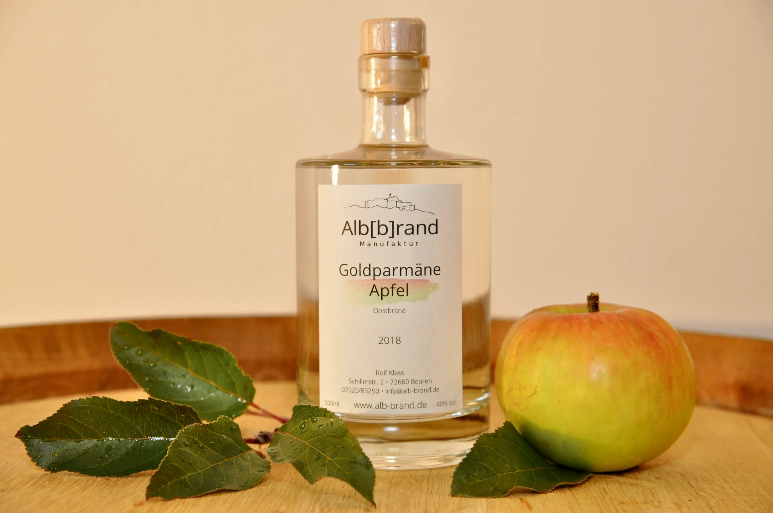 Flasche Apfelbrand Goldparmäne mit Apfel auf einem Holzfass